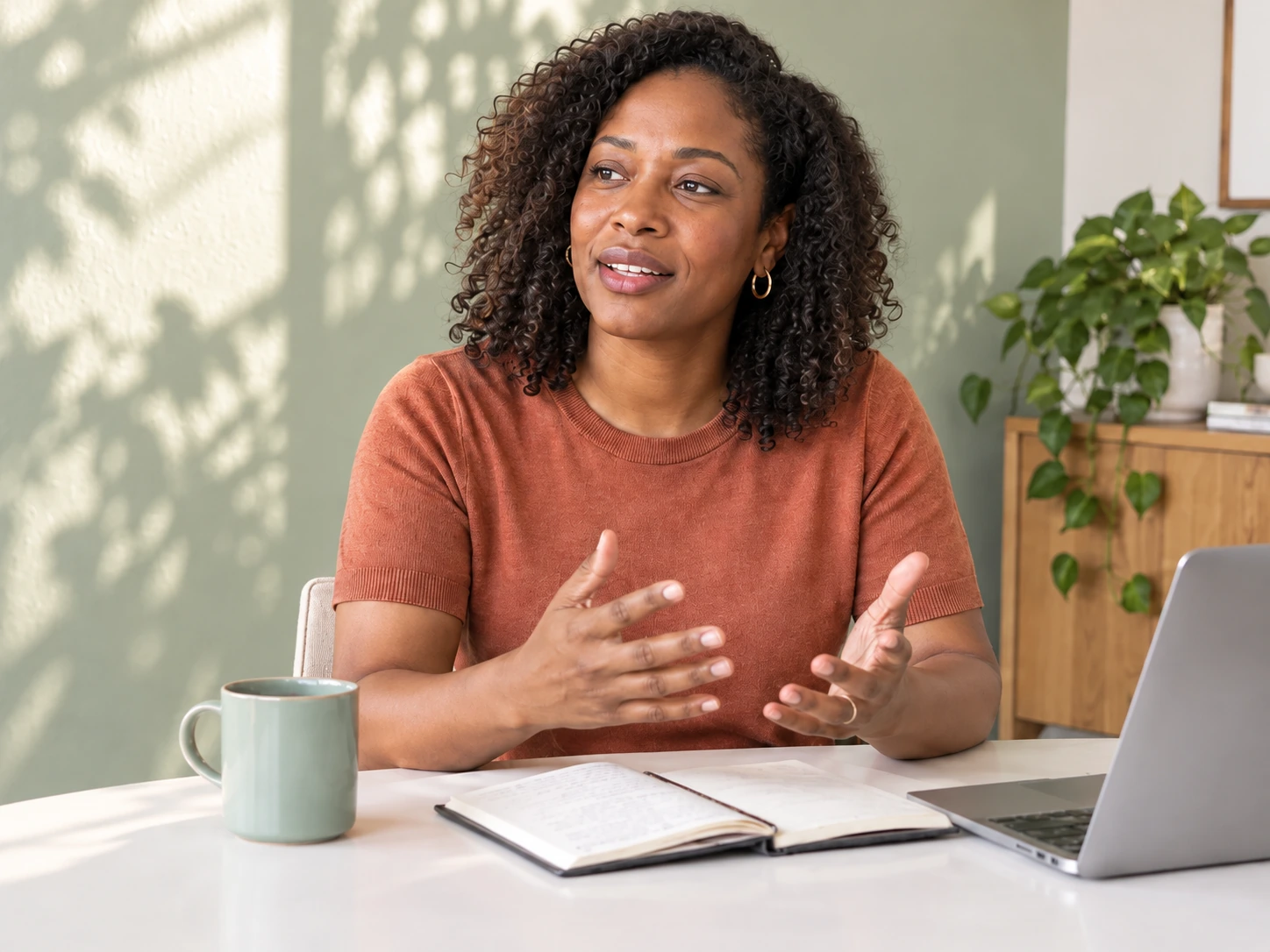 A career coach speaking on a laptop call, with an open notebook in front of her