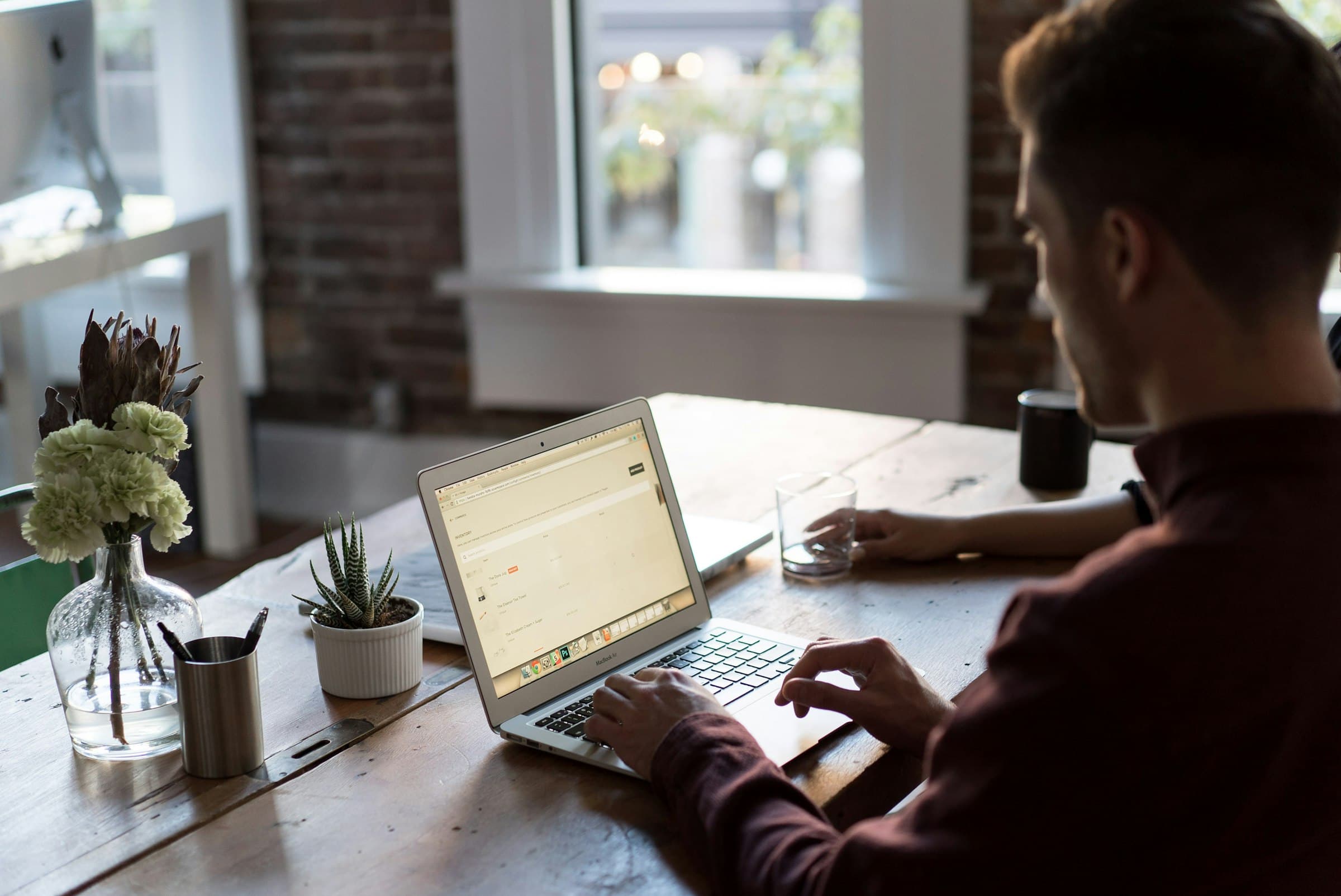 A manager at a desk by a window, working, plants behind