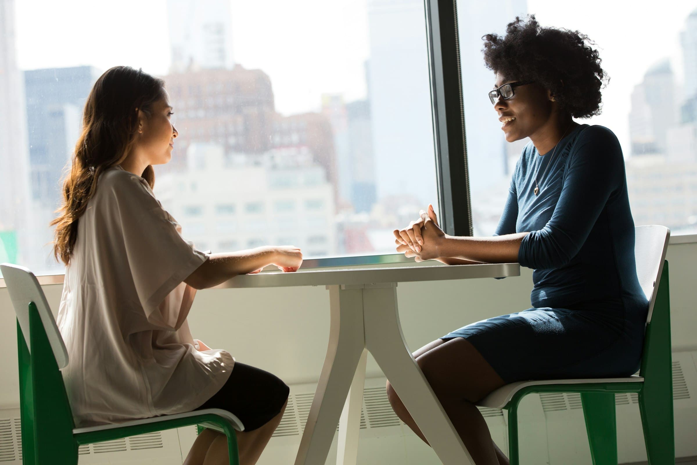 Two colleagues at a small table by a window at the end of a meeting